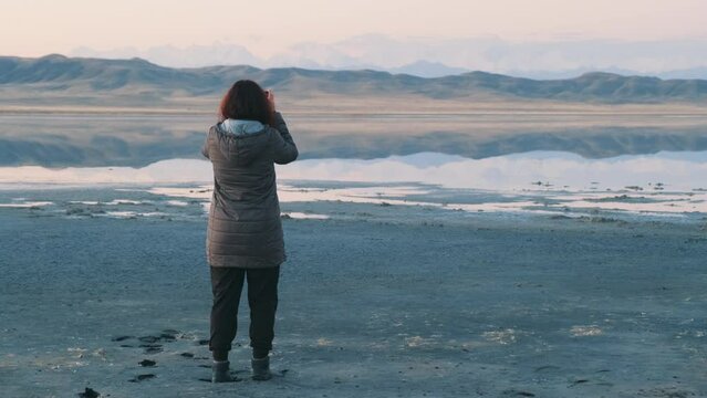 A woman takes a pictures of Tuz Kol lake on a mobile phone