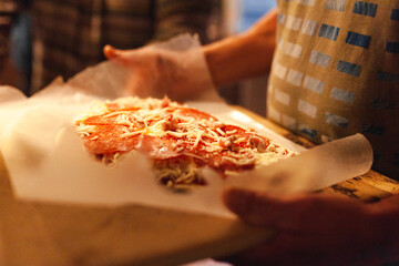 Close up of a hands holding a homemade pizza