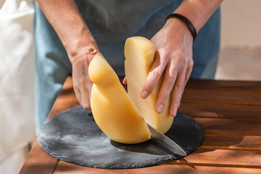 female hand's cutting a caciocavallo silano cheese on a cutting board