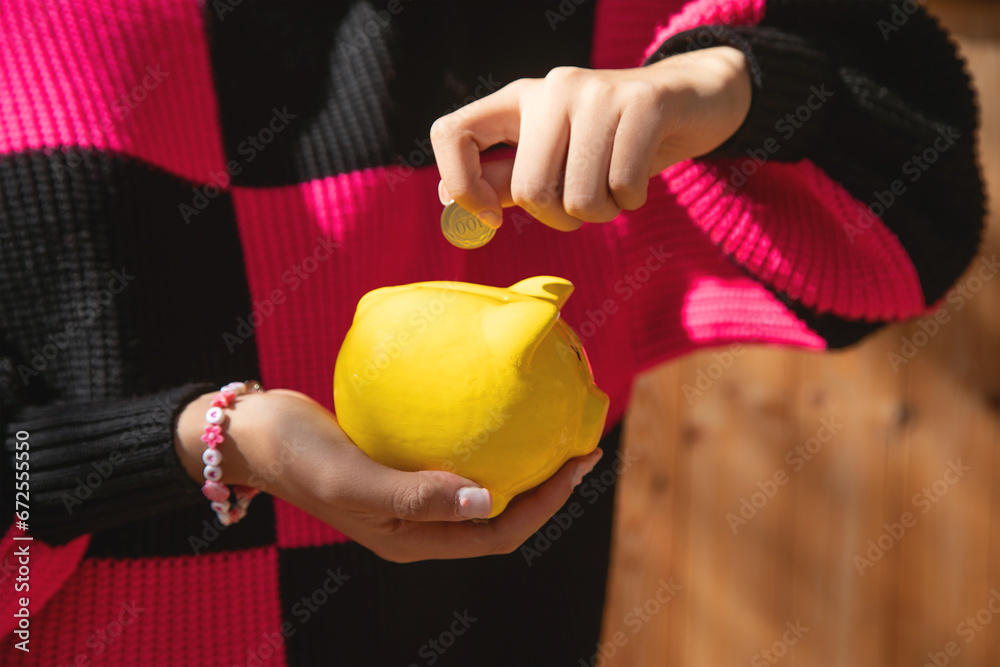 Poster caucasian young woman holding a piggy bank.