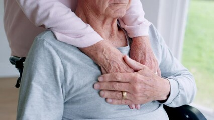 Love, support and couple holding hands in wheelchair by window for thinking in living room at home. Comfort, compassion and closeup of elderly man with disability and woman in retirement at house.