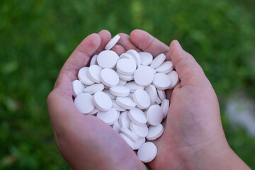 A handful of white round pills in his hands. Medications. Pills.
