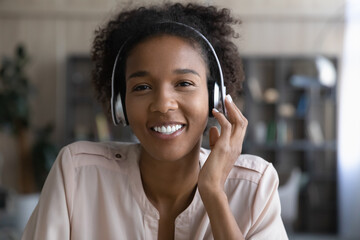 Screen view head shot of happy young African American student girl wearing headphones looking at camera, smiling at webcam. Video call portrait of teen millennial gen Z blogger, coach giving training - obrazy, fototapety, plakaty