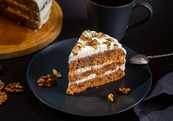 Carrot cake with butter cream and walnuts on a dark background.