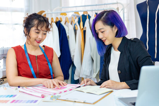 Team of fashionable freelance dressmakers choosing design and pantone for new custom made dress while working in the artistic workshop studio for fashion design and clothing business industry
