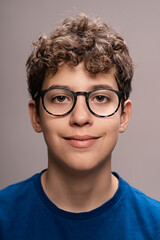 Teenage boy with glasses portrait - Young male smiling headshot: Happy adolescent with curly hair