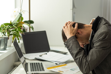 Photo portrait of tired guy having headache holding nose bridge with fingers at table in modern industrial office indoors