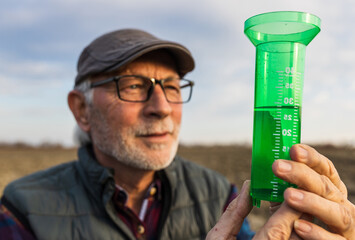 Farmer measuring water quantity in field by rain gauge