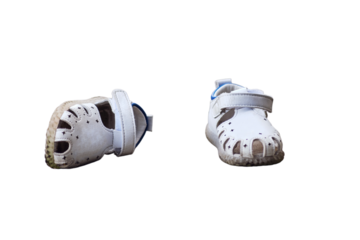 Pair of white baby shoes on the pavement, lost children boots, isolated on white background