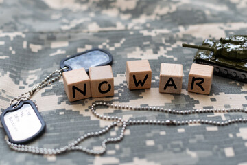 phrase no war is laid out of wooden squares on a gray background with flag of ukraine with blue and yellow ribbon. Concept of peace, war in Ukraine