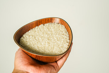 rice in a wooden bowl held by hand, zakat concept