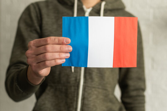 close up hand holding french flag on studio isolated white background