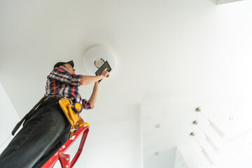 Electrician man worker installing ceiling lamp