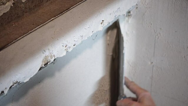 Male builder use metal spatula for putty walls, repairman filling spatula with spackling paste and covering cement wall surface. Builder leveling wall and angle Renovation work in Residential Premises