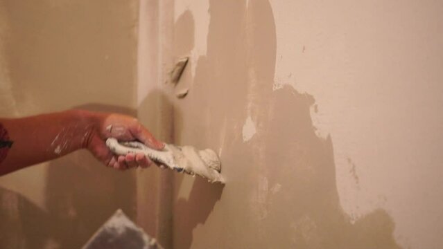 Male builder use metal spatula for putty walls, repairman filling spatula with spackling paste and covering cement wall surface. Builder leveling wall and angle Renovation work in Residential Premises