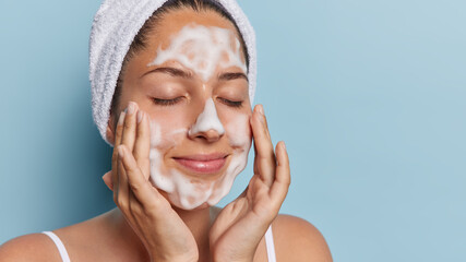 Proper hygiene and pampering concept. Headshot of young woman has facial cleansing routine enjoying...