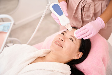 Obraz na płótnie Canvas Woman undergoing ultrasonic facial cleansing in a cosmetology salon