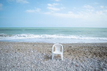 Scenic view of single plastic chair against sea - obrazy, fototapety, plakaty