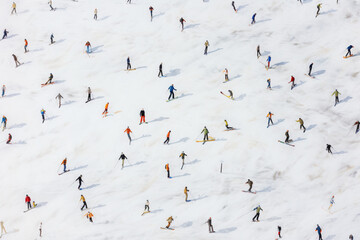 Aerial view of unrecognizable skiers on mountain ski slope skiing downhill and enjoying winter sport activity
