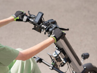 A woman controls a wheelchair using a special manual device. Close-up of female hands on electric handbike. 