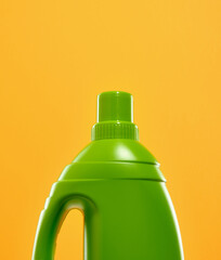 A green bottle of laundry detergent stands on a brightly colored background. Laundry day on weekend.