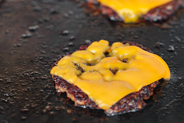 Beef patty chop covered with piece of cheese fried on baking sheet, close-up, selective focus