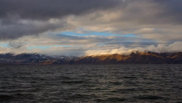 Daytime Timelapse of moving white, grey clouds over lake Sevan on background hills