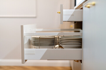 Open kitchen drawers with porcelain plates neatly organized. Storage organization system in kitchen 