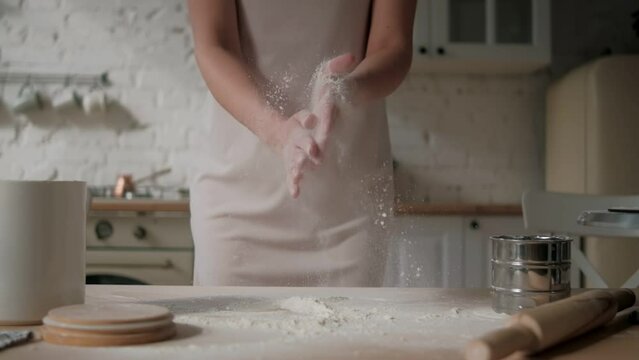 Chef hands clapping hands with flour in super slow motion. Woman cooking pastry. Baking dust and particles flying in air. Concept of cookery and bread baking