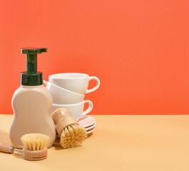 Set of clean kitchen ceramic tableware. Detergent dispenser and dishwashing brushes. Copy space for text.