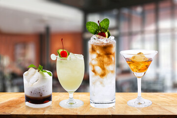 A variety of classic cocktails with garnishes in each glass.Four colorful cocktails on a wooden table at the bar,Celebrate success, holiday, luxury,  blurred background. Blurry background.