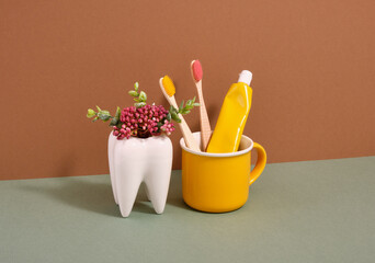 Dental concept and white tooth stand. Environmental toothbrushes and toothpaste stand in a yellow cup.
