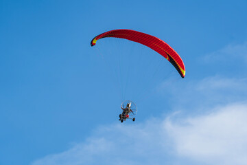 Flying with paramotor in the blue sky - Man riding paramotor in the blue sky background