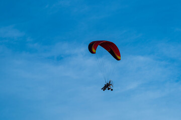 Flying with paramotor in the blue sky - Man riding paramotor in the blue sky background