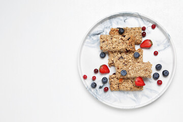 Tasty granola bars and berries on white background, top view. Space for text