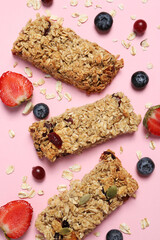 Fototapeta premium Tasty granola bars and ingredients on pink background, flat lay