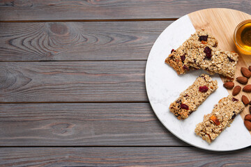 Tasty granola bars and ingredients on grey wooden table, top view. Space for text