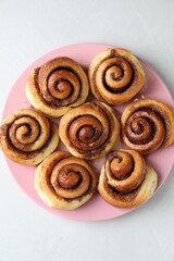 Many tasty cinnamon rolls on white table, top view