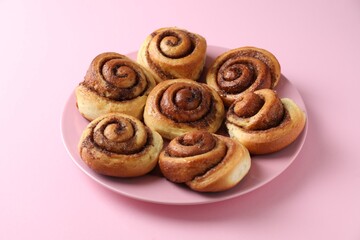 Many tasty cinnamon rolls on pink background, closeup