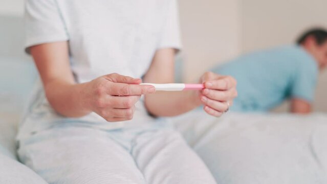 Woman, pregnancy test and hands for future, bedroom and anxiety or worry for healthcare. Couple, fail contraception and mistake for positive home maternity kit, fear or nervous thinking for baby
