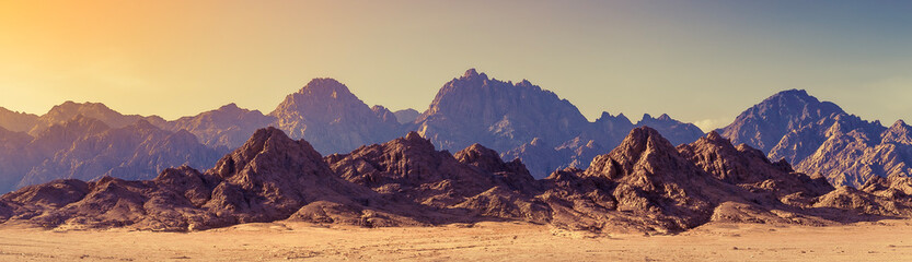 Panoramic landscape of mountain peaks in soft light on golden sunset time. Wide landscape with...