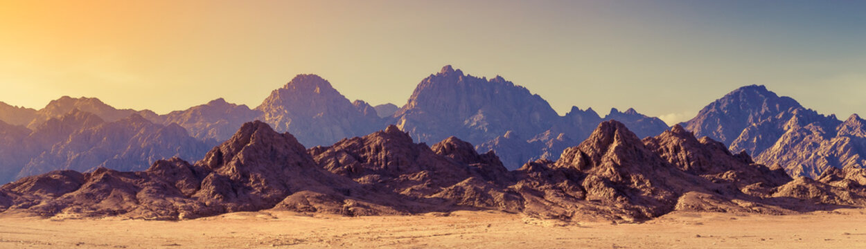 Panoramic landscape of mountain peaks in soft light on golden sunset time. Wide landscape with mountains in a desert, Africa.