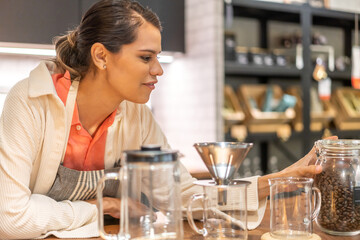 Portrait of barista woman small business owner working behind the counter bar and  receive order from customer on coffee packaging and cup of coffee background in cafe or coffee shop