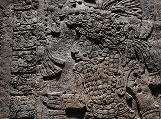 Bas relief carving in a stele tombstone of a mayan ruler king with maya hieroglyph writing symbols,...