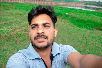 Happy moment of a handsome young boy taking selfie on grass background