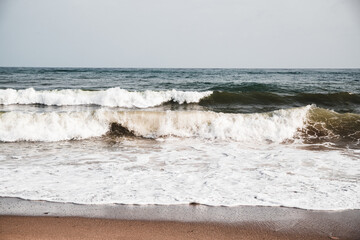 View at sea waves on a beach with massive foam, nature background.