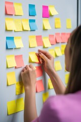 Woman organizer attaches colorful sticky notes with reminders of important things to white board