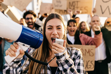 Large group of diverse people manifesting against war or attack on a country. Female activist using megaphone outdoors. Stop war signs and banners in a peace demonstration - obrazy, fototapety, plakaty