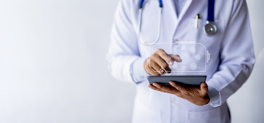 Male Doctor Wearing Scrubs In Hospital Corridor Using Digital Tablet
