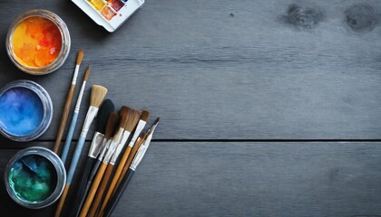 Art creative table background with watercolor paints palette paintbrushes pencils supplies tools on grey wooden desk, artist gray design blank workspace top view from above, flat lay, copy space
 - obrazy, fototapety, plakaty